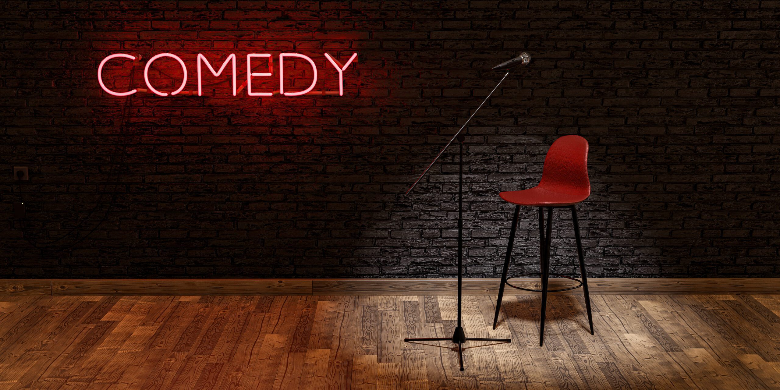 Stage with microphone and stool illuminated by a spotlight with the word COMEDY on a red neon lamp and brick wall.