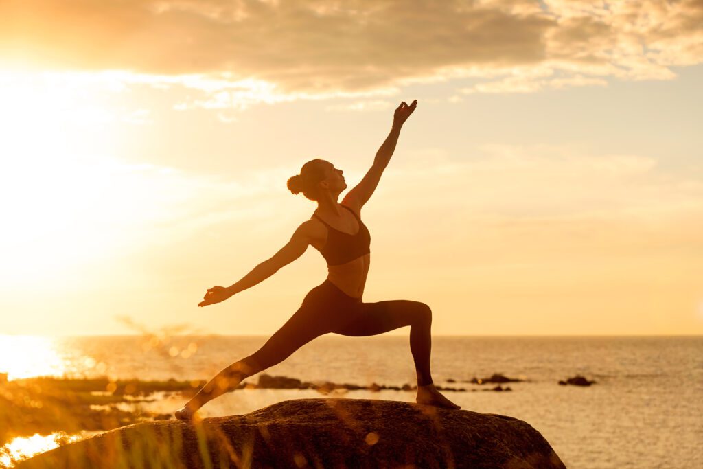 Fitness woman practicing yoga at sunset