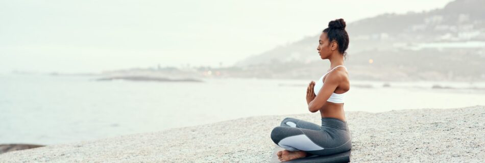 Shot of a sporty young woman practicing yoga at the beach